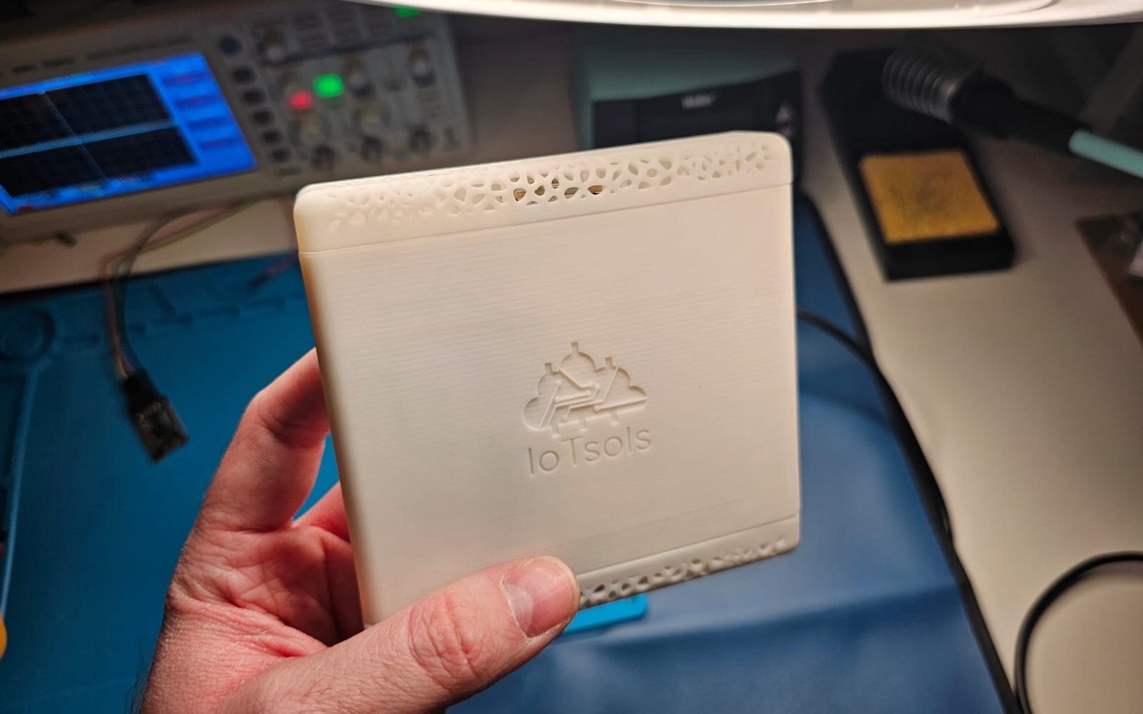 The printed enclosure held at the bench, with an oscilloscope and soldering station behind